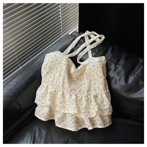 Detail of floral spaghetti strap top with layered ruffles on a black leather surface