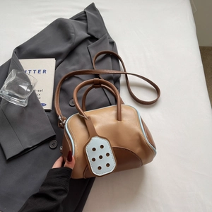 Two-tone brown Boston bag with blue trim and shoulder strap on grey blazer