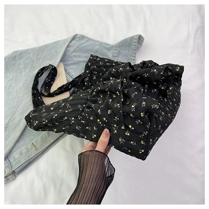 Detail of black floral tote bag with yellow flowers and textured pleated top closure