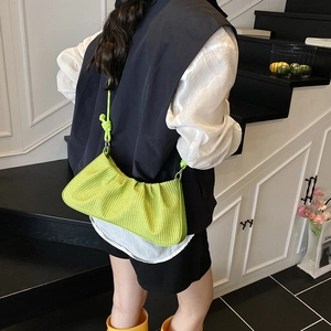 Neon green pleated dumpling bag with knot handle shown on model in minimal interior