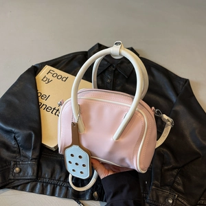 Chic pink and white contrast bowling bag with racket charm on a leather jacket