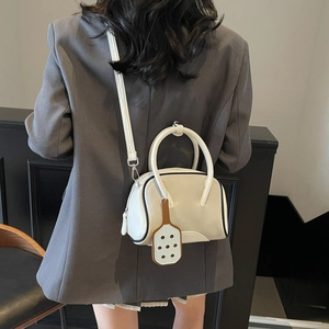 Chic beige macaron-style crossbody bag with tennis racket charm and rounded handle