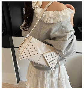 Détail d'un sac à bandoulière blanc crème avec rivets argentés et rabat asymétrique