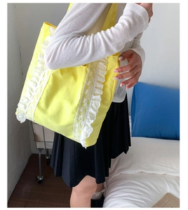 Model wearing yellow canvas tote bag with white lace ruffles and long shoulder strap
