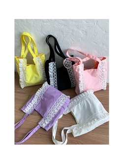 Close-up of five colorful canvas tote bags with lace details on a light wood floor