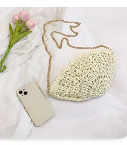 Detail of cream straw woven shoulder bag showing hollow knit pattern and gold metal chain