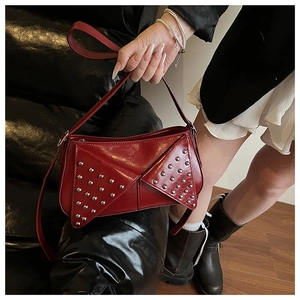 Gros plan du sac à bandoulière rouge brillant avec rivets argentés et sangle réglable