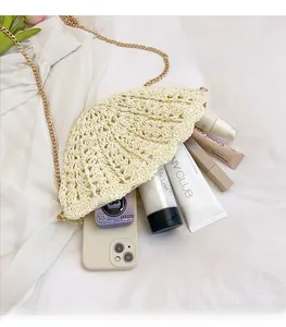 Detail of beige straw shell bag interior with golden chain and spacious storage