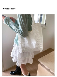Detail of white canvas tote bag featuring delicate lace edges and pleated ruffles decoration