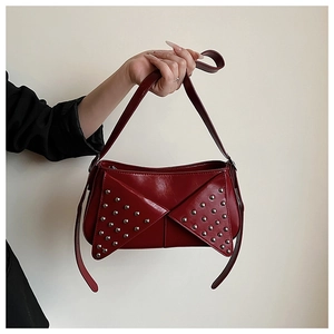 Détail du sac à bandoulière rouge foncé avec clous argentés et texture cuir PU brillant