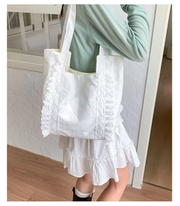 Close-up of white canvas tote bag featuring layered lace ruffles and pleated edge details
