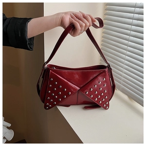 Detailed close-up of a dark red faux leather handbag with silver rivets and unique design