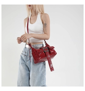Detailed view of red patent leather shoulder bag featuring utility pockets and rivets