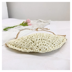 Detail of a creamy woven straw bag with a half-moon pattern and golden chain strap