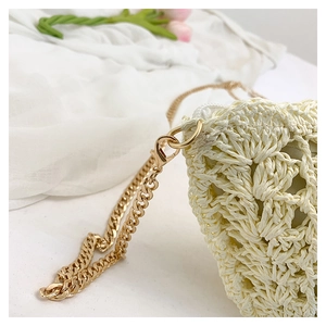 Detail of woven straw bag with gold metal chain strap and white zipper closure