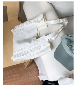 Detail shot of white canvas tote bag with delicate lace frills and pleated texture