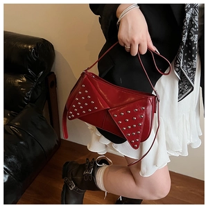 Macro detail of dark red glossy leather handbag with silver punk style rivets and straps