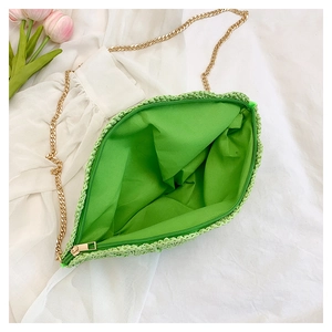 Detail of green straw bag with zip closure, matching inner lining and gold chain strap