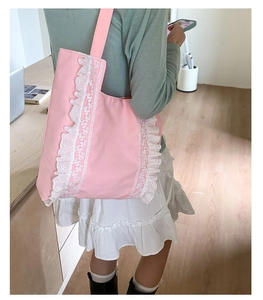 Detailed view of pink canvas tote bag with delicate white lace ruffles and shoulder straps