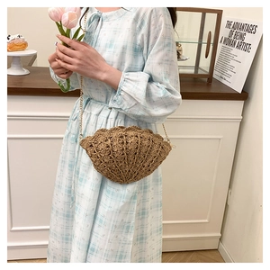 Detail of shell-shaped straw crossbody bag with natural woven texture and gold metal chain