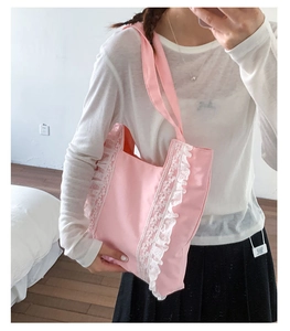 Detailed view of pink canvas tote bag with delicate white lace trim and shoulder straps