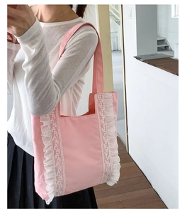 Detail of light pink canvas tote bag featuring white lace trim and ruffled edges