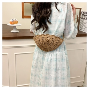 Detailed texture of shell-shaped straw woven crossbody bag with gold chain strap