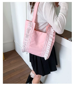 Detailed view of pink canvas tote bag with white lace trim and long shoulder straps