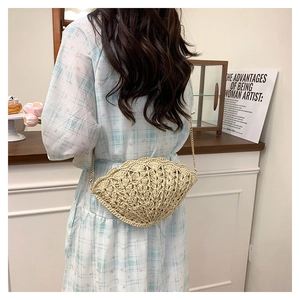 Detail of hand-woven beige straw crossbody bag with unique shell texture and gold chain strap
