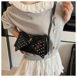 Close-up of black glossy shoulder bag featuring silver rivets and punk-style envelope flap