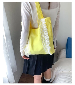 Detailed view of yellow canvas tote bag with elegant white floral lace embroidery details