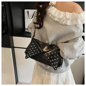 Close-up of black patent leather bag featuring silver rivets in geometric triangle patterns