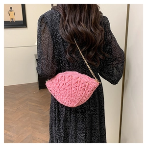 Detail of pink shell-shaped woven crossbody bag with elegant gold metal chain strap