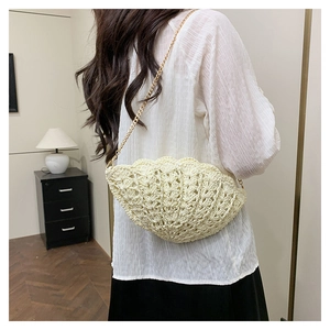 Detailed close-up of a shell-shaped woven straw crossbody bag with gold chain strap
