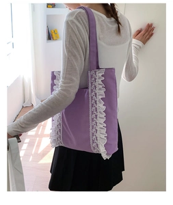 Detailed view of white lace trim decor on a purple canvas tote bag shoulder strap