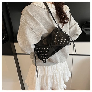 Détail d'un sac à bandoulière triangle noir avec des clous argentés sur cuir PU brillant