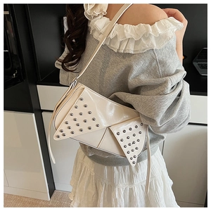 Detailed close-up of punk style cream leather bag featuring silver metallic rivet studs