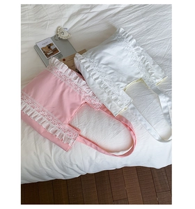 Detail of pink and white canvas tote bags featuring elegant lace trim on a soft surface