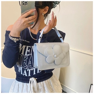 Close-up of a light blue rectangular bag featuring a large 3D floral accent on the flap