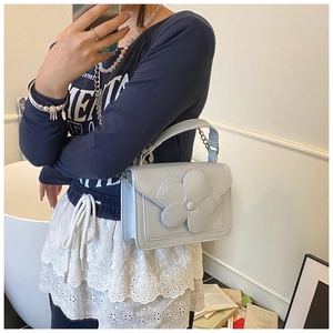 Detailed view of light blue crossbody bag with a large 3D floral accent and chain strap