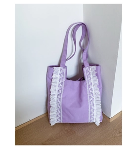 Detail of light purple canvas tote with vertical white lace trim and long shoulder straps
