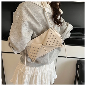 Detail of cream leather bag featuring geometric flap and silver stud embellishments