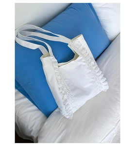 Close-up of white canvas tote bag with elegant lace trim and ruffled edge details