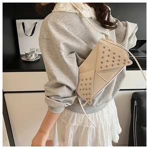 Détail du sac bandoulière géométrique crème avec clous argentés et rabat de style enveloppe