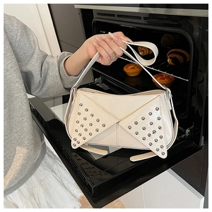 Détail du sac en cuir verni blanc crème avec rivets argentés et rabats uniques