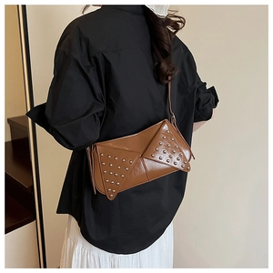 Close-up of brown leather crossbody bag with silver rivet studs and geometric flap design
