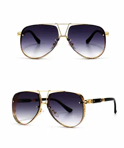 Detail view of golden metal sunglasses frame with intricate relief and grey gradient lenses