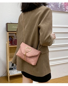 Detailed close-up of pink quilted crossbody bag with gold heart clasp and chain strap