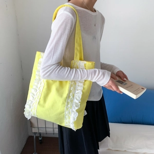 Japanese style yellow canvas tote bag with white lace trim shown on a female model