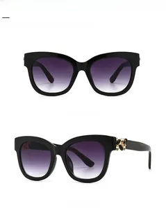 Détail de lunettes de soleil œil-de-chat noires avec décor floral doré en strass